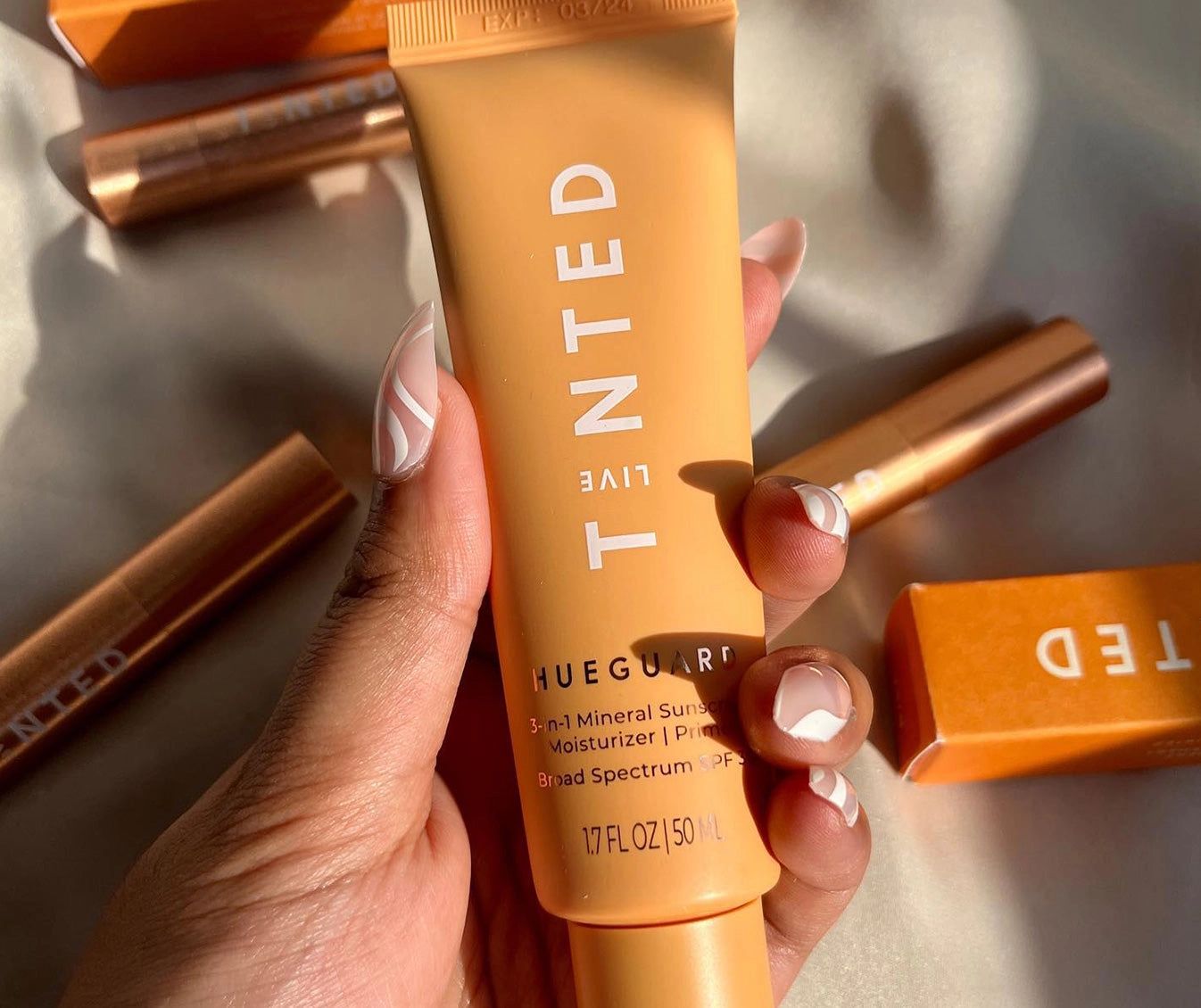 Hand holding a HUEGUARD® tube next to its orange box
